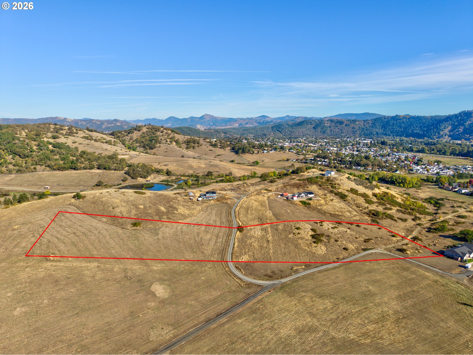 Aerial view of the Wil Way parcel, rolling land and gravel road; outline is approximate