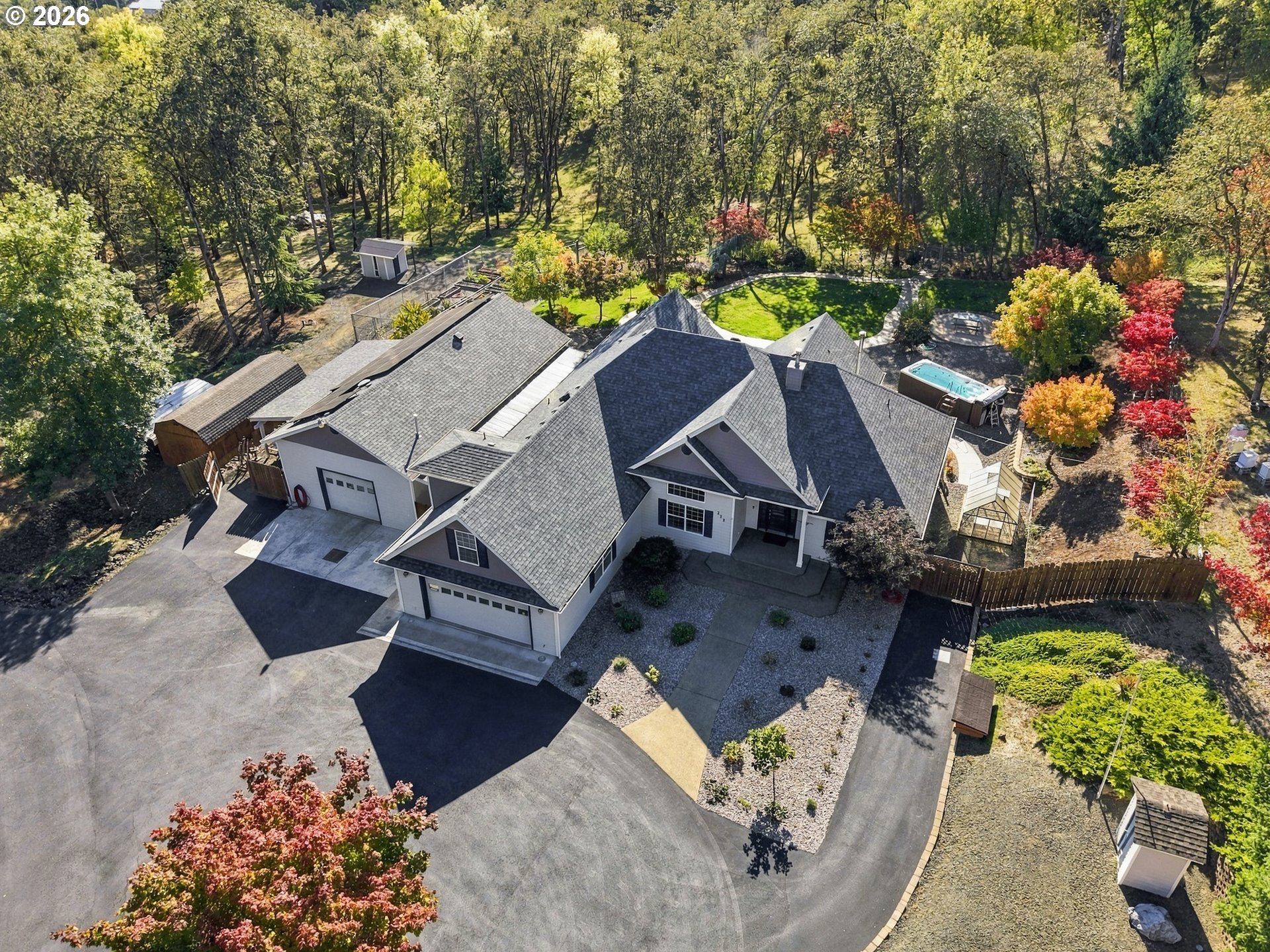 Aerial view of 711 Sable Dr showing the home, driveway, landscaped yard and wooded hills in Roseburg, Oregon