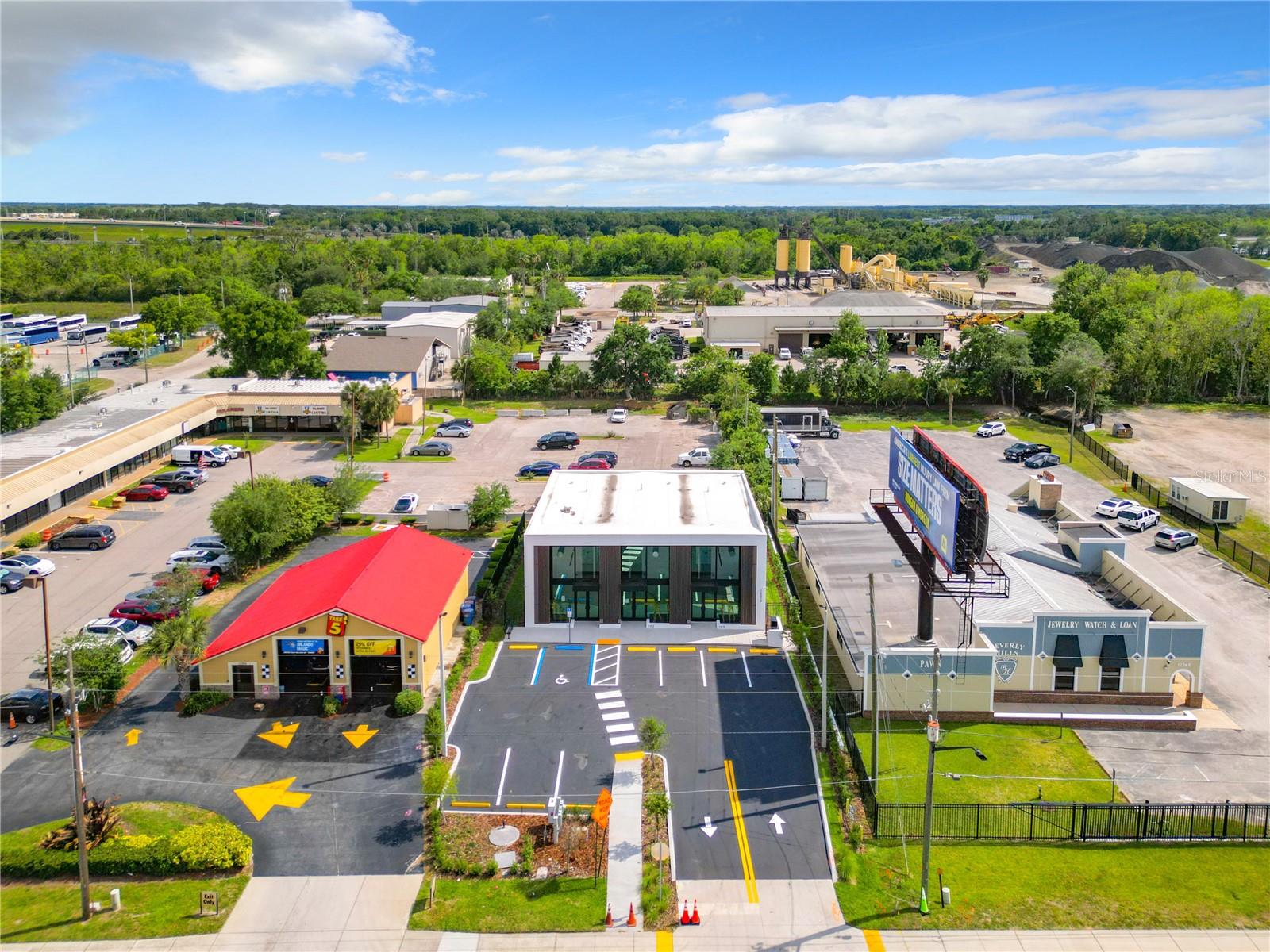 Sunset rendering of 12324 W Colonial Drive in Winter Garden, FL — modern minimalist single-story spec office building with white stucco facade, wood-slat cladding, recessed glass storefronts, and warm architectural uplighting