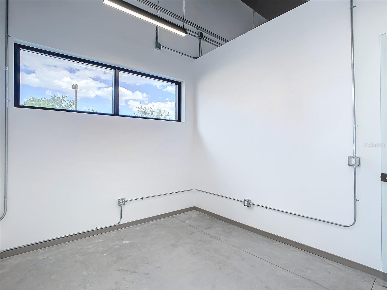 Sunset rendering of 12324 W Colonial Drive in Winter Garden, FL — modern minimalist single-story spec office building with white stucco facade, wood-slat cladding, recessed glass storefronts, and warm architectural uplighting