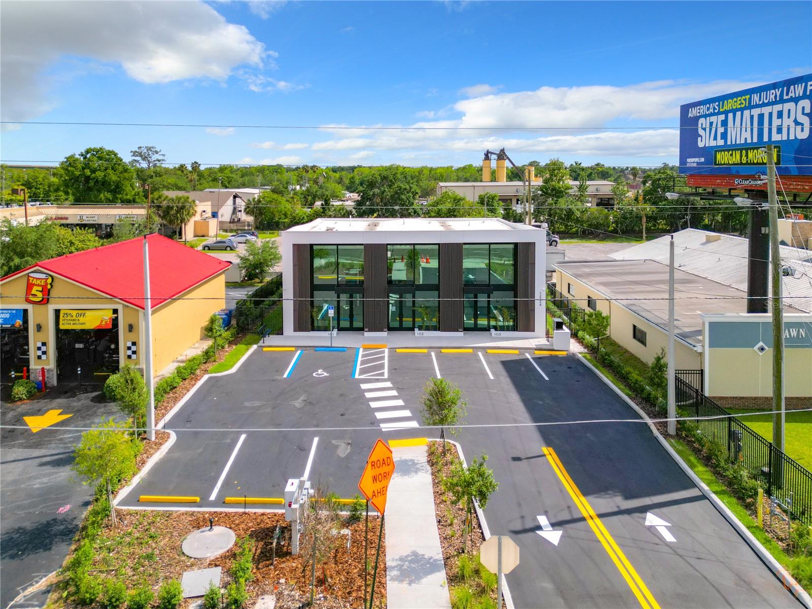 Sunset rendering of 12324 W Colonial Drive in Winter Garden, FL — modern minimalist single-story spec office building with white stucco facade, wood-slat cladding, recessed glass storefronts, and warm architectural uplighting