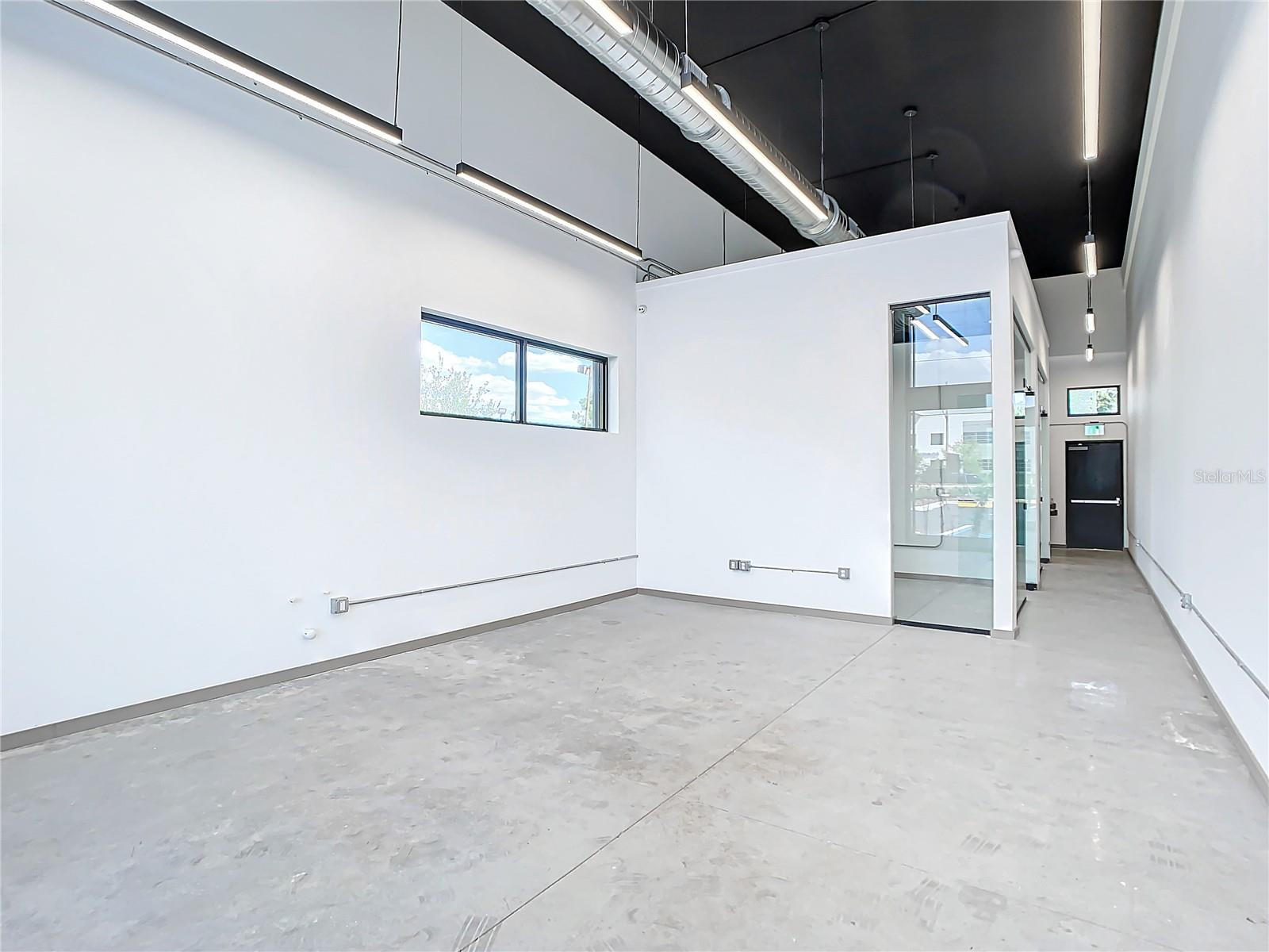 Sunset rendering of 12324 W Colonial Drive in Winter Garden, FL — modern minimalist single-story spec office building with white stucco facade, wood-slat cladding, recessed glass storefronts, and warm architectural uplighting