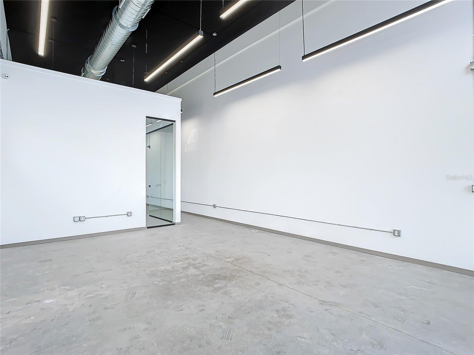 Sunset rendering of 12324 W Colonial Drive in Winter Garden, FL — modern minimalist single-story spec office building with white stucco facade, wood-slat cladding, recessed glass storefronts, and warm architectural uplighting