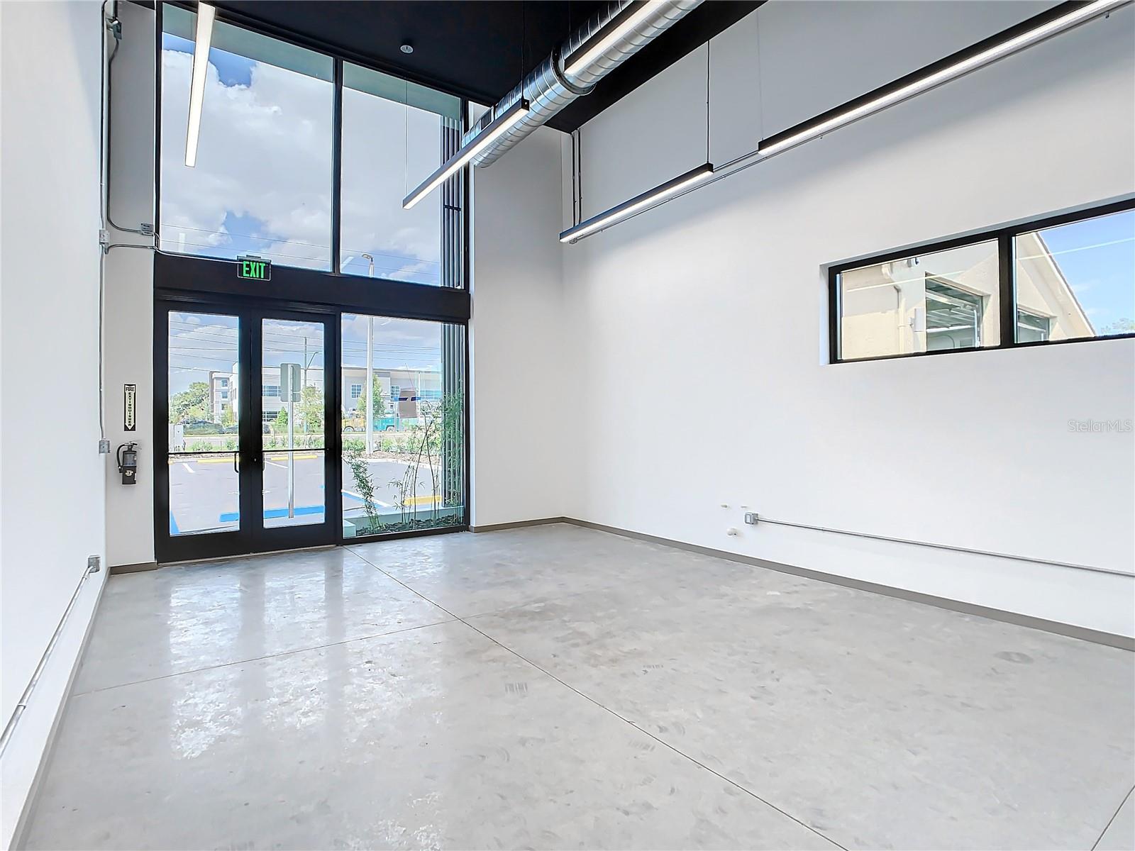 Sunset rendering of 12324 W Colonial Drive in Winter Garden, FL — modern minimalist single-story spec office building with white stucco facade, wood-slat cladding, recessed glass storefronts, and warm architectural uplighting