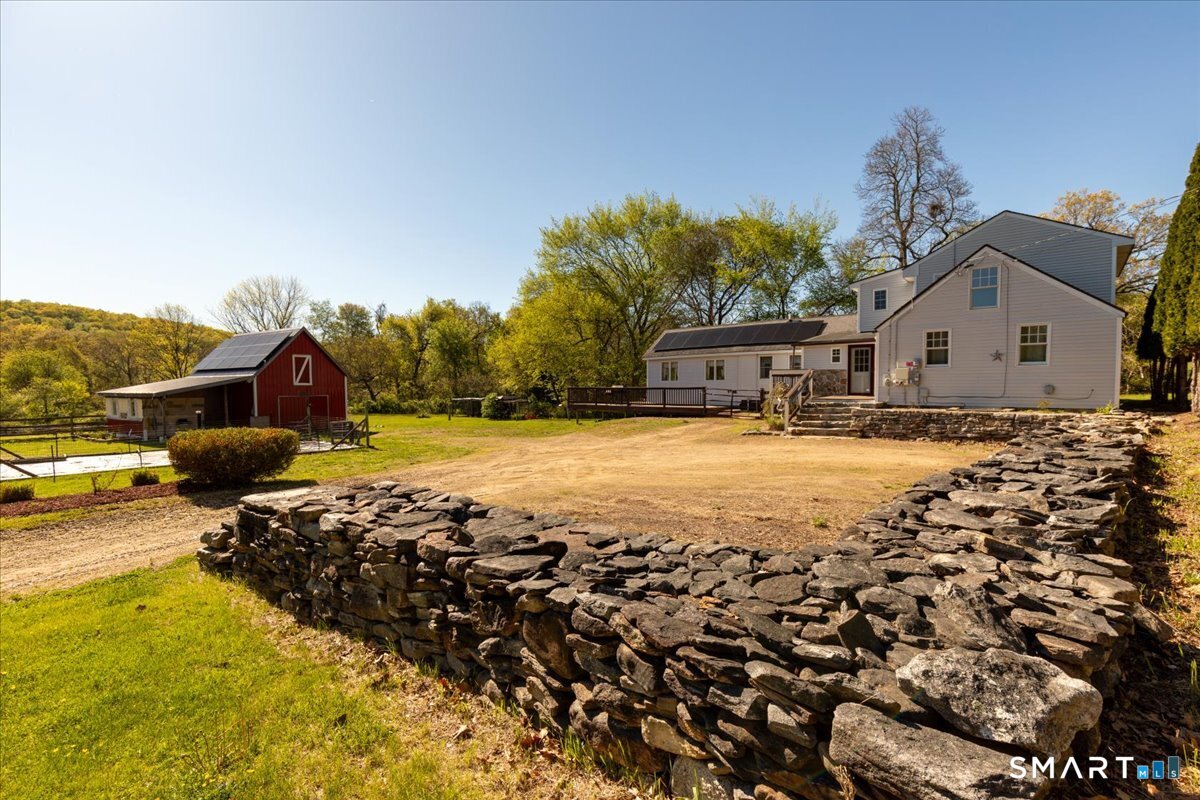Charming Connecticut property with covered porch, well-maintained exterior, mature trees surrounding home