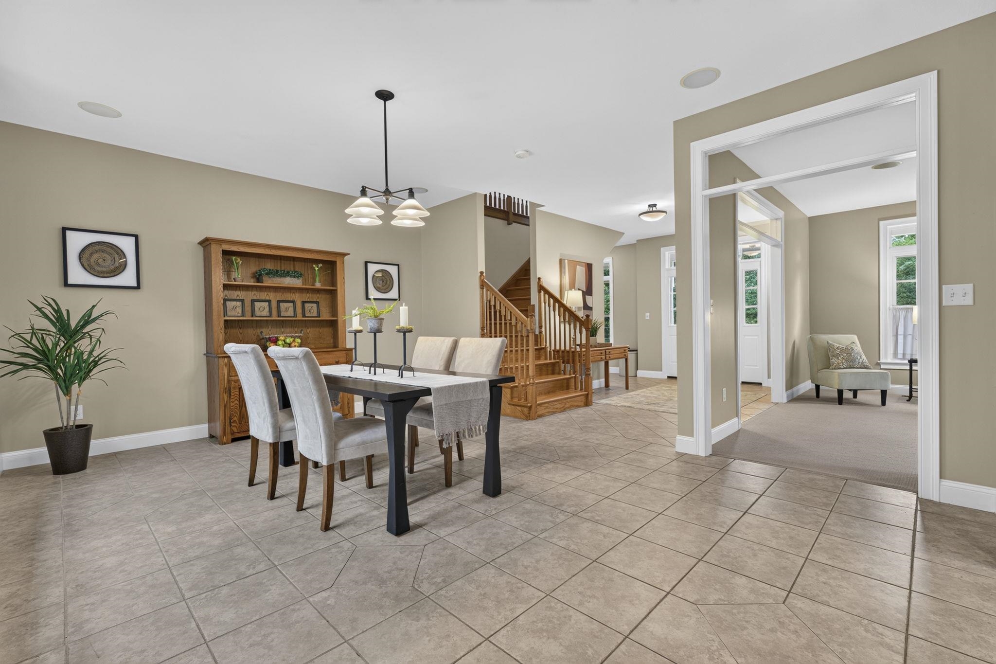 Open dining area with chandelier, tile floor and staircase inside 122 Island Pond Road